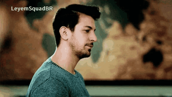 a man in a blue sweater is standing in front of a map with the words leyemsquadbr written above him