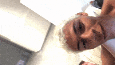 a man with white hair is laying on a bed and smiling