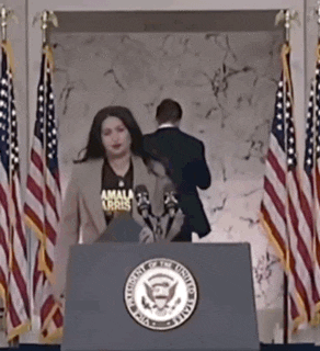 a woman stands at a podium wearing a tshirt that says amala abris