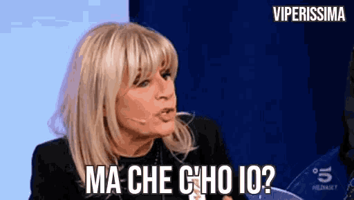 a woman with blonde hair and bangs is talking into a microphone and says ma che c'ho io ?