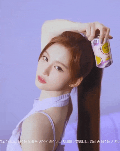 a woman in a purple tank top is holding a can of lemonade