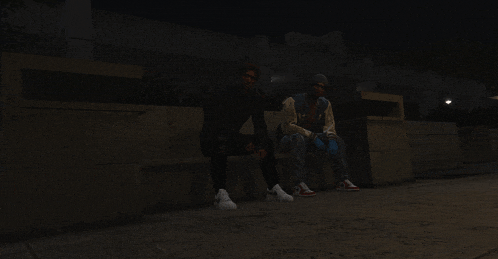 two men sit on a bench in a dark room