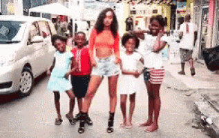 a woman is standing next to a group of children on the sidewalk .
