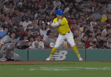 a baseball player swings his bat in front of a new balance advertisement