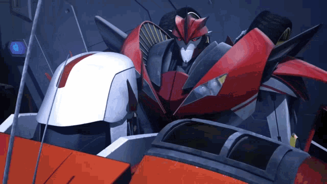 a red and white robot is standing next to a white robot