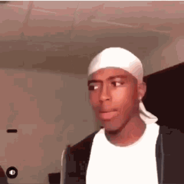 a young man wearing a white headband and a black jacket is making a funny face .