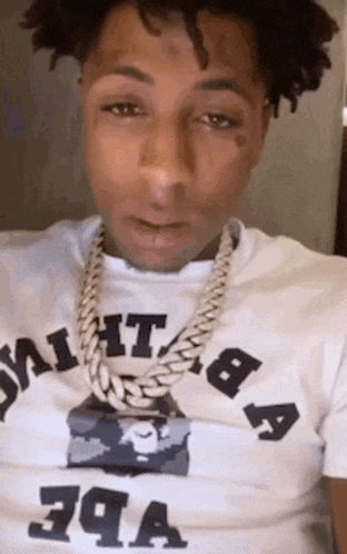 a man wearing a white shirt and a gold chain around his neck .
