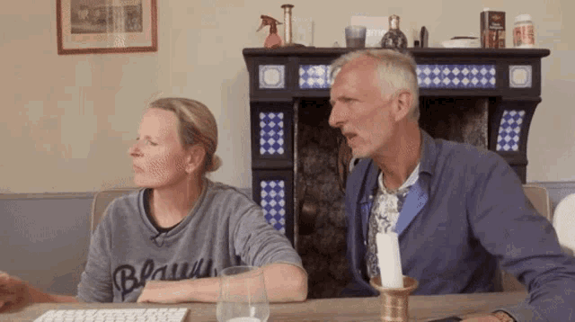 a man and a woman sit at a table with a man wearing a shirt that says bruin