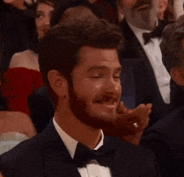 a man in a tuxedo and bow tie is smiling in a crowd