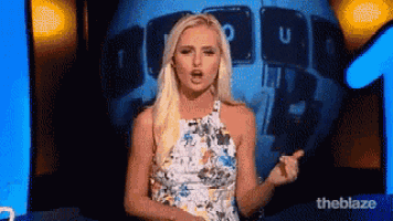 a woman in a floral dress is standing in front of a screen that says the blaze