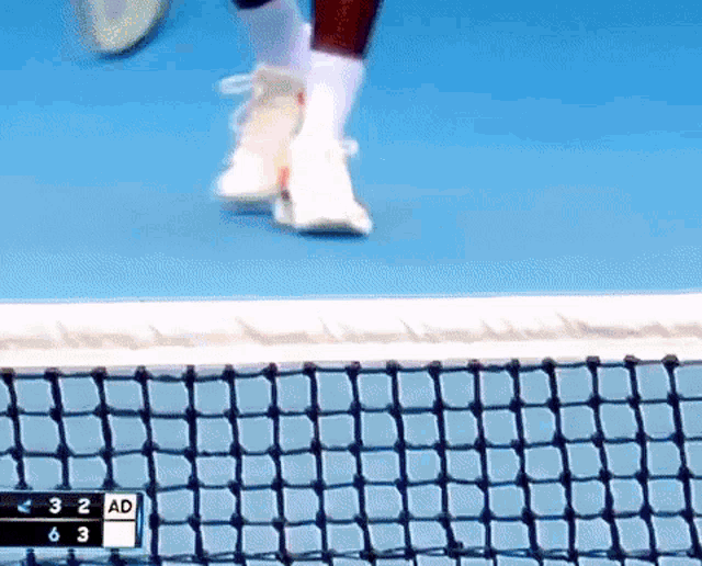 a tennis player 's feet are shown on a tennis court with the scoreboard showing ad