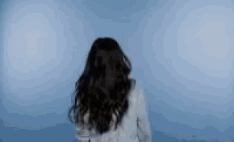 a woman with long hair is standing in front of a blue background .