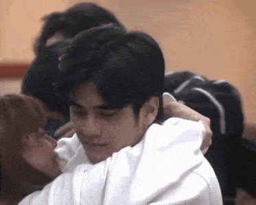 a man in a white shirt is hugging a woman in a black shirt