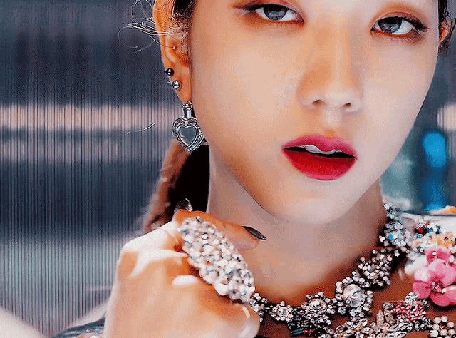 a woman wearing a heart shaped earring and a necklace