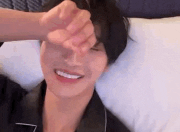 a man is laying in bed with his hand on his forehead .
