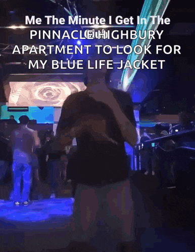 a man in a black shirt is standing in front of a crowd in pinnacle highbury apartment to look for his blue life jacket .