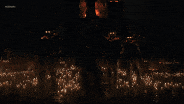a group of soldiers are standing in front of a burning church with fireworks in the background