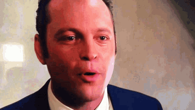 a man in a blue suit and white shirt is making a funny face .