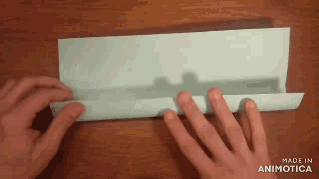 a person 's hands folding a piece of paper with the words made in animotica visible