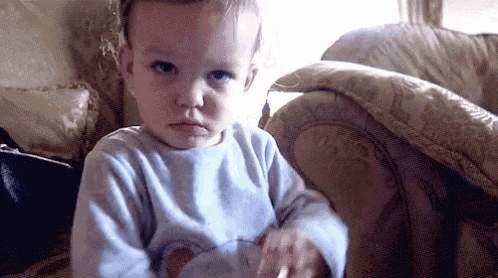 a baby is sitting on a couch and making a funny face