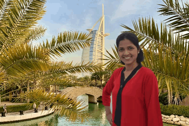 a woman in a red shirt is standing in front of a palm tree