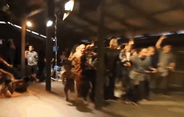 a group of people are dancing in a dark room under a roof .