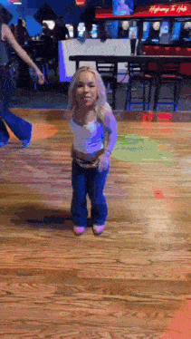a little girl is dancing on a wooden floor in front of a highway to hell sign