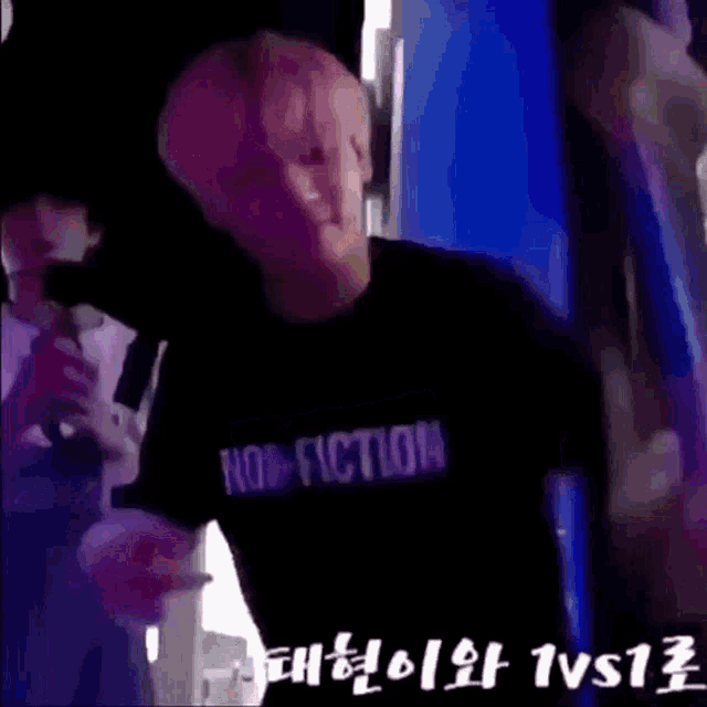 a man wearing a black t-shirt that says fiction is standing in front of a microphone .