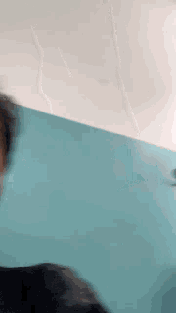 a blurry picture of a person 's face with a blue wall in the background