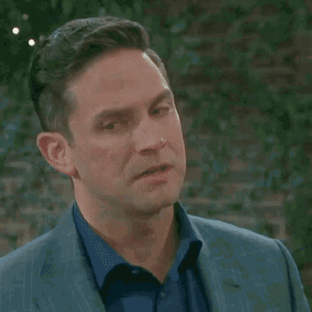 a man in a suit and blue shirt is making a surprised face .
