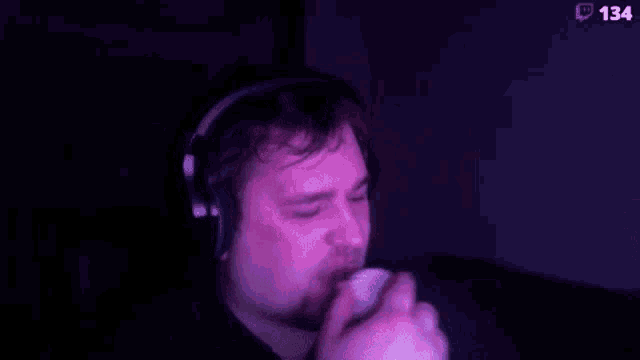 a man wearing headphones is eating an ice cream cone in a dark room .