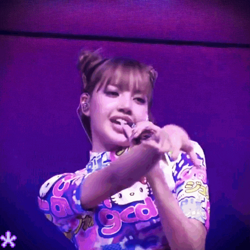 a woman is singing into a microphone while wearing a colorful shirt that says ggo
