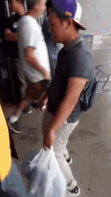 a man in a purple hat is carrying a bag