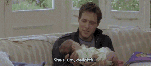a man is holding a baby while reading a book .
