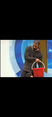 a man is holding a red bucket in front of a blue background