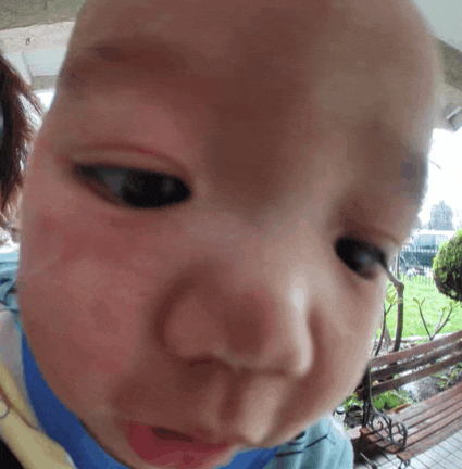 a close up of a baby 's face with a blue shirt on