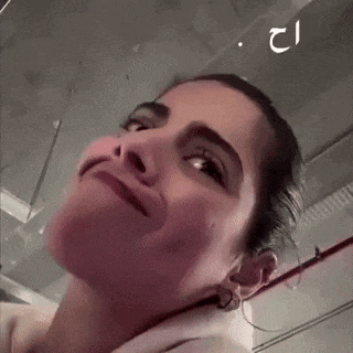 a close up of a woman 's face making a funny face in a parking garage .