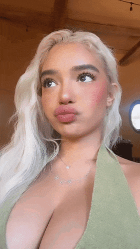 a woman with blonde hair is wearing a green tank top and a necklace