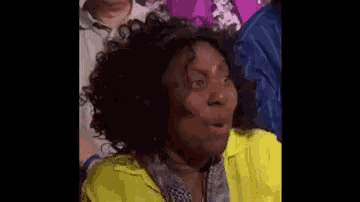 a woman in a yellow shirt and scarf is making a funny face .