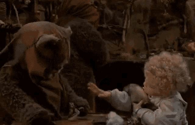 a doll is sitting at a table with a stuffed animal and talking to it .