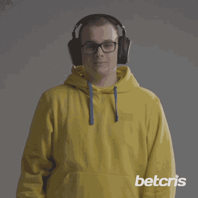 a man wearing headphones and a yellow hoodie with the word betcris on it