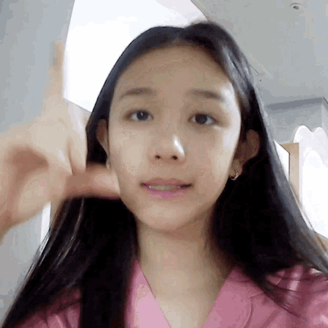 a woman with long black hair is wearing a pink shirt