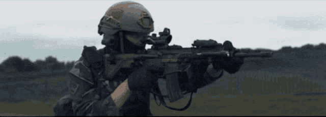 a soldier is holding a gun in a field .