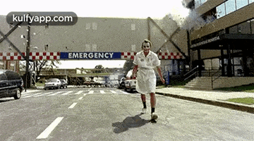 the joker is walking down the street in front of an emergency entrance