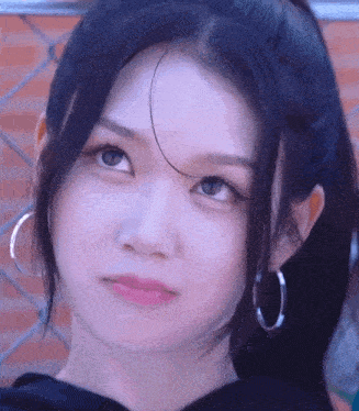 a close up of a woman 's face with hoop earrings and a ponytail .