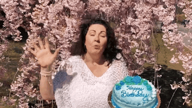 a woman blows a kiss while holding a cake that says happy birthday