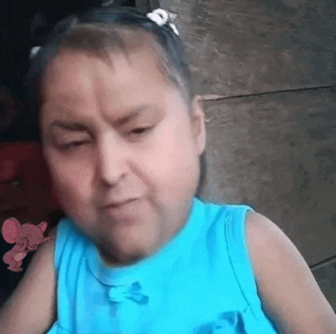 a little girl in a blue dress is making a face .