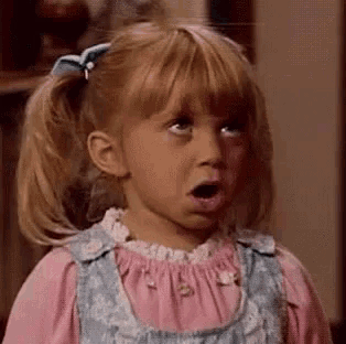a little girl with pigtails is making a funny face .