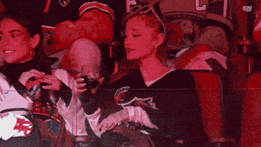 a woman sits in the stands at a hockey game wearing a jersey that says ' sharks ' on it