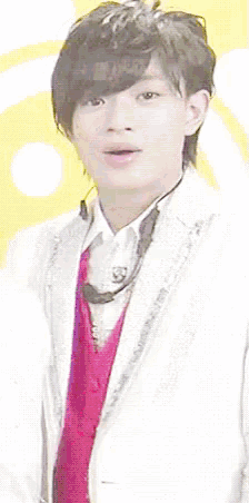 a young man wearing a white suit and a red sweater